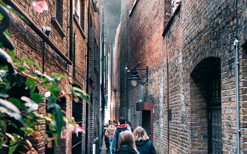 People walking through a narrow alley in London, reminiscent of Harry Potter film locations.
