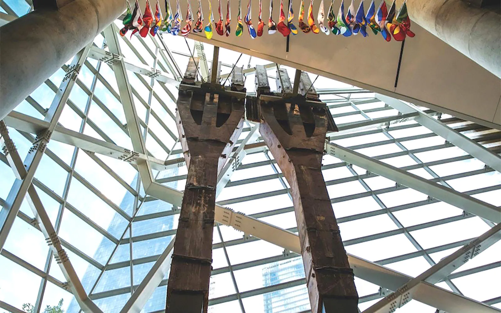 Steel tridents inside 9/11 Memorial Museum, New York City, with flags above.
