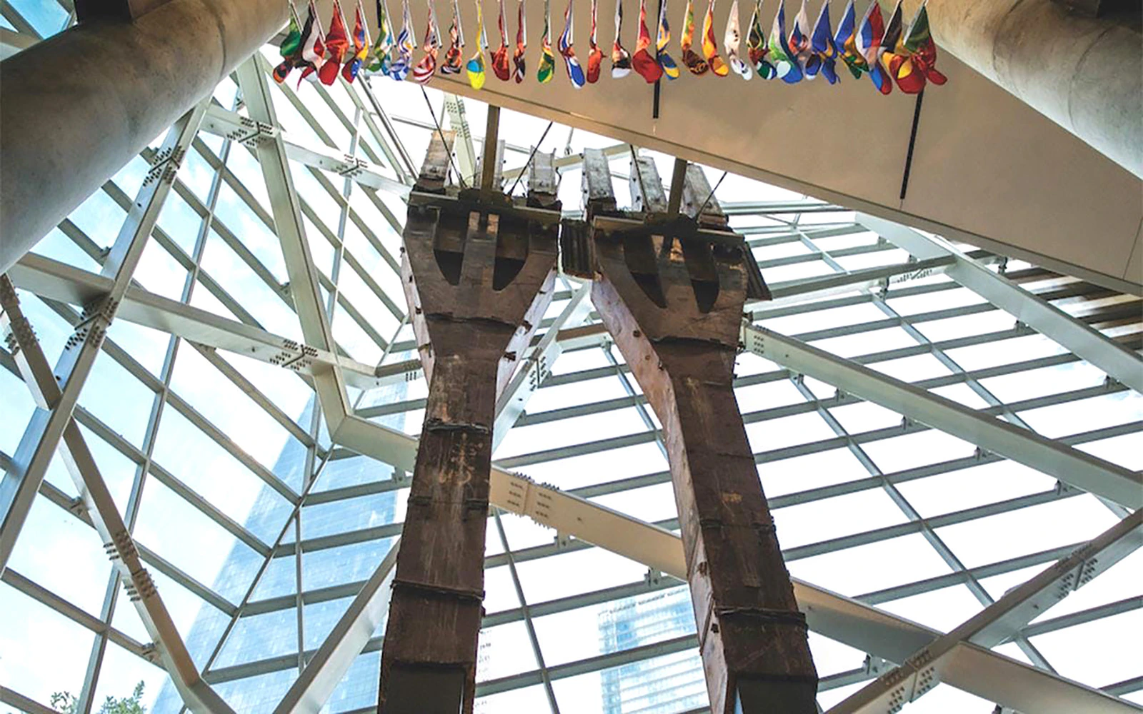 Steel tridents inside 9/11 Memorial Museum, New York City, with flags above.