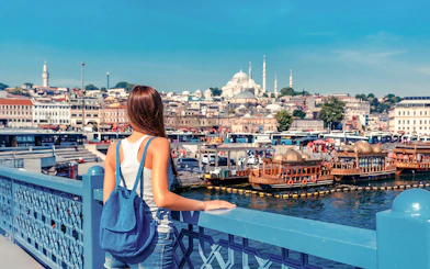 Woman overlooking the Golden Horn from Galata Bridge, Istanbul with Suleymaniye Mosque in view.