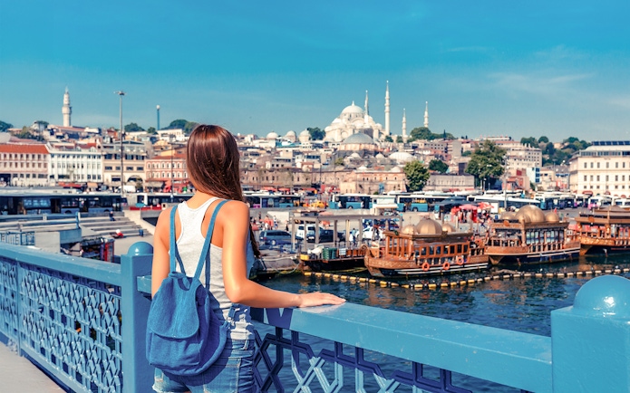 Woman overlooking the Golden Horn from Galata Bridge, Istanbul with Suleymaniye Mosque in view.