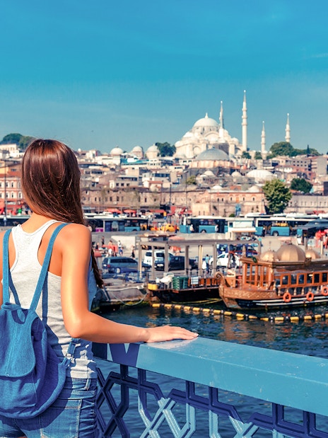 Woman overlooking the Golden Horn from Galata Bridge, Istanbul with Suleymaniye Mosque in view.