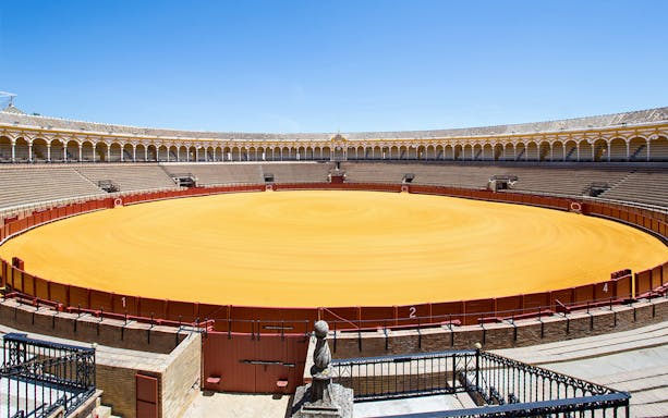 Seville bullfight arena with empty stands and central sand ring.