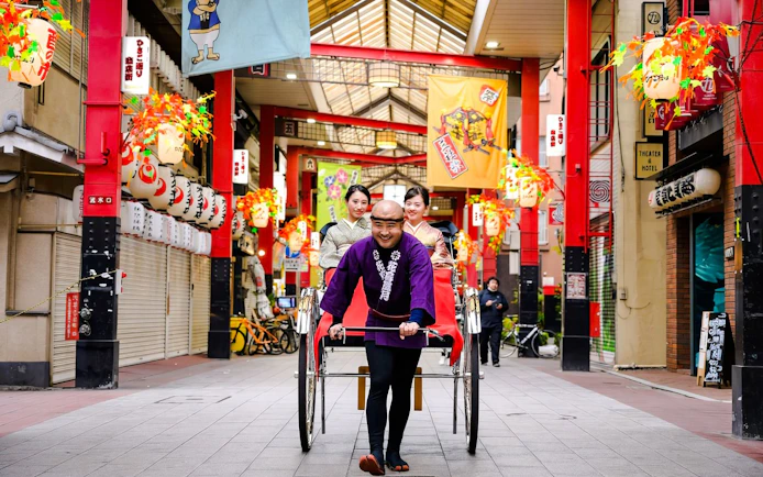 Rickshaw driver pulling passengers through Asakusa shopping arcade, Tokyo.