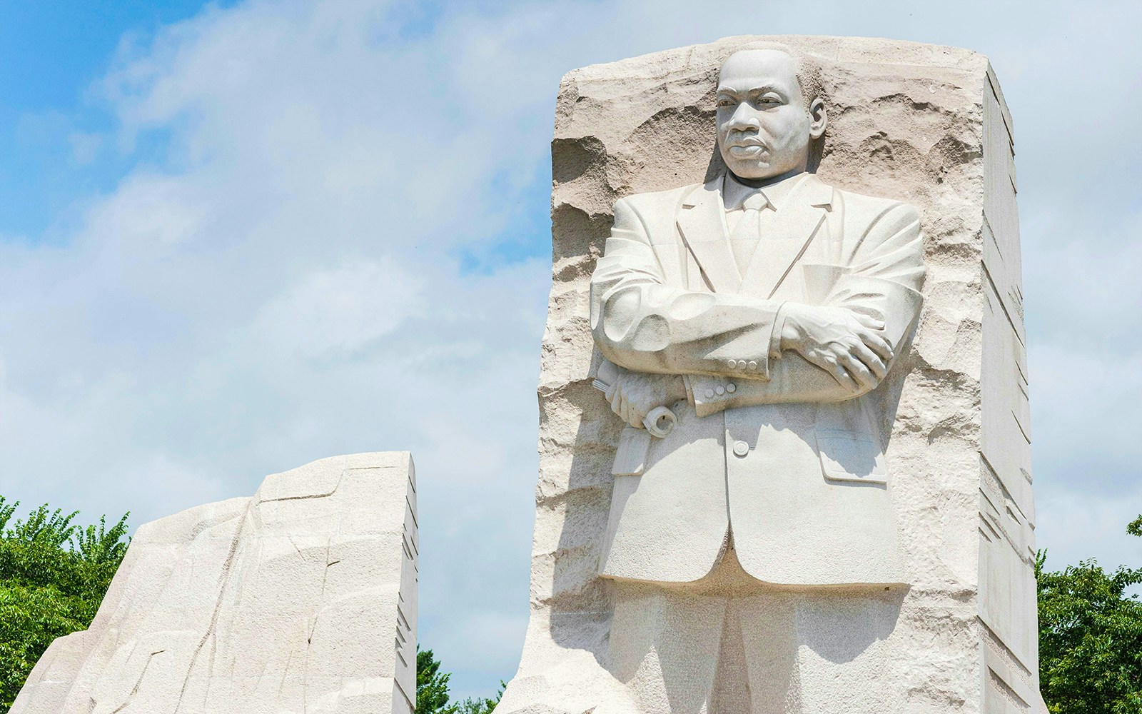 Martin Luther King Jr. Memorial statue in Washington DC against a blue sky.
