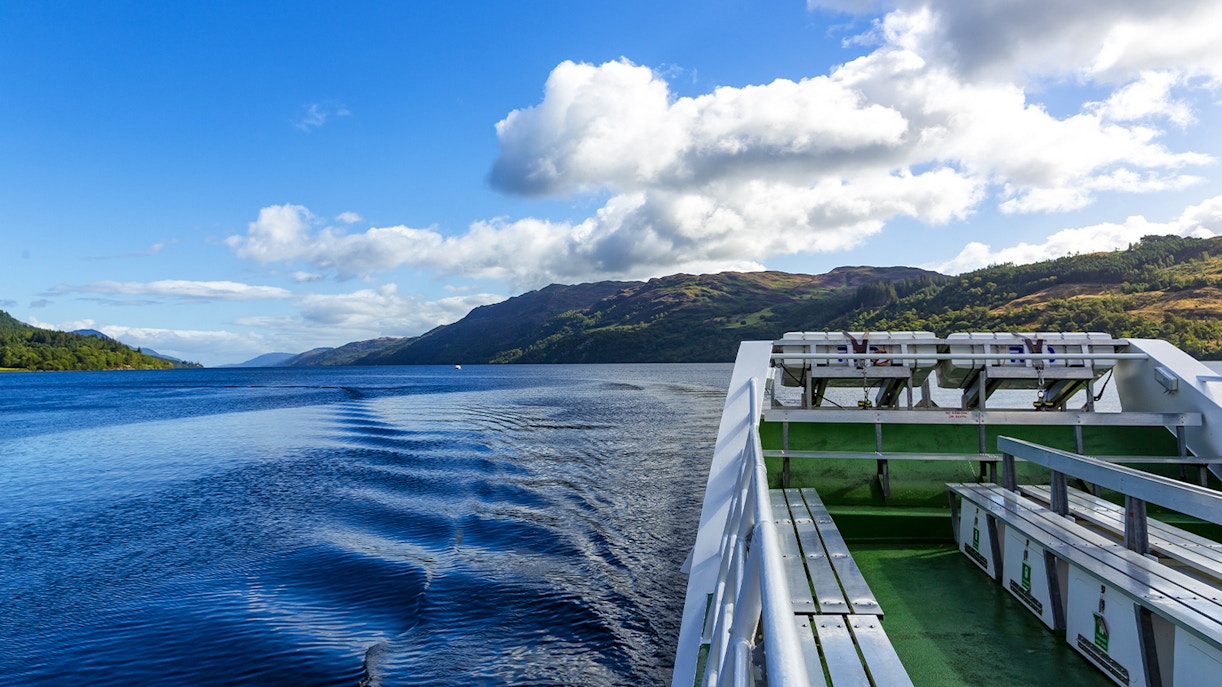 Cruise ship deck overlooking Loch Ness with scenic hills in Scotland.