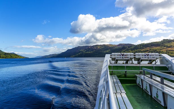 Cruise ship deck overlooking Loch Ness with scenic hills in Scotland.