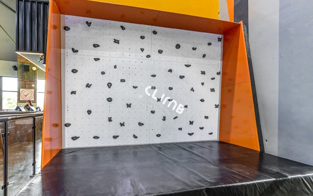 Indoor climbing wall at Adrenark Adventure with safety mat and climbing holds.