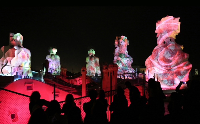 Casa Mila rooftop sculptures illuminated during La Pedrera Night Experience in Barcelona.