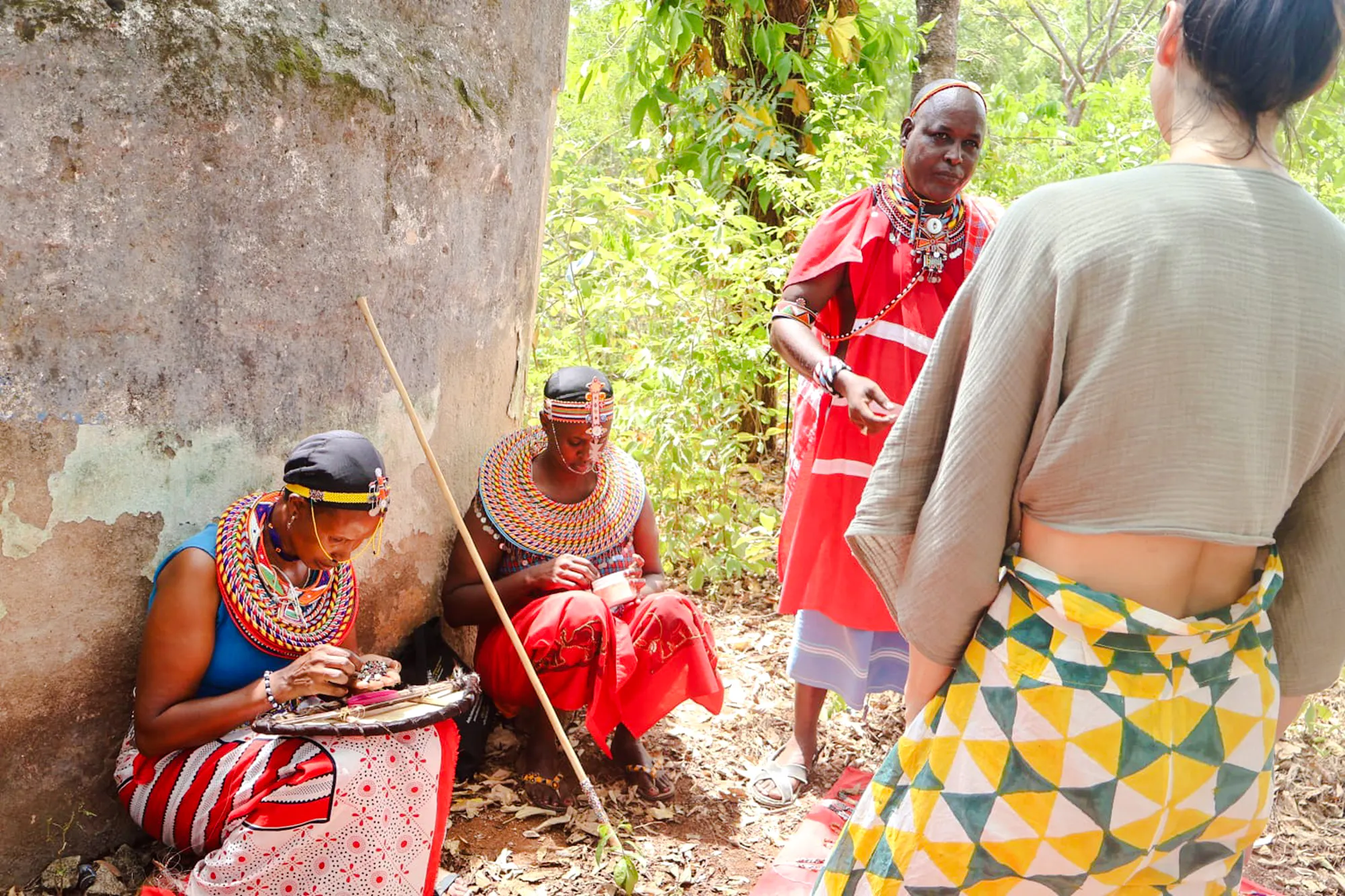 Maasai women in traditional attire crafting jewelry, Diani Beach cultural tour.