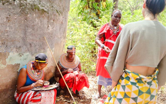 Maasai women in traditional attire crafting jewelry, Diani Beach cultural tour.