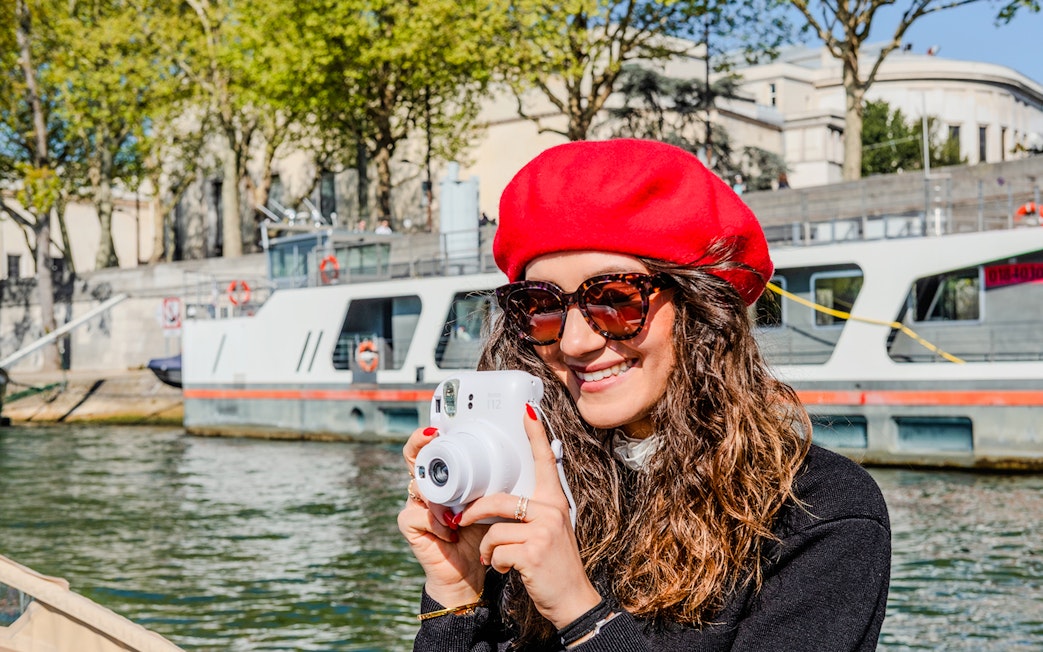 Person taking a Polaroid photo on the Seine River during the Emily in Paris Champagne Cruise.