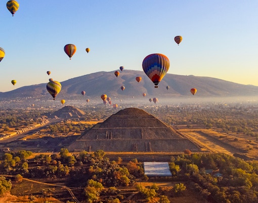 Hot air balloons at sunrise over Teotihuacan pyramid, Mexico.