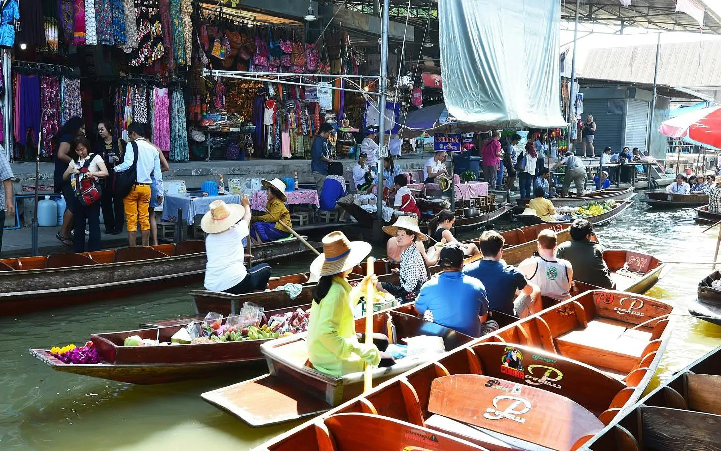 Boats with tourists and vendors at Damnoen Saduak Floating Market near Bangkok, showcasing local goods.