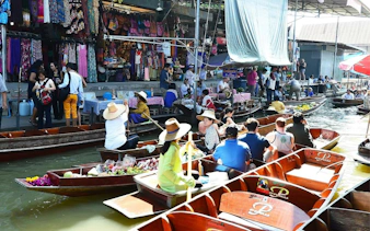 Boats with tourists and vendors at Damnoen Saduak Floating Market near Bangkok, showcasing local goods.