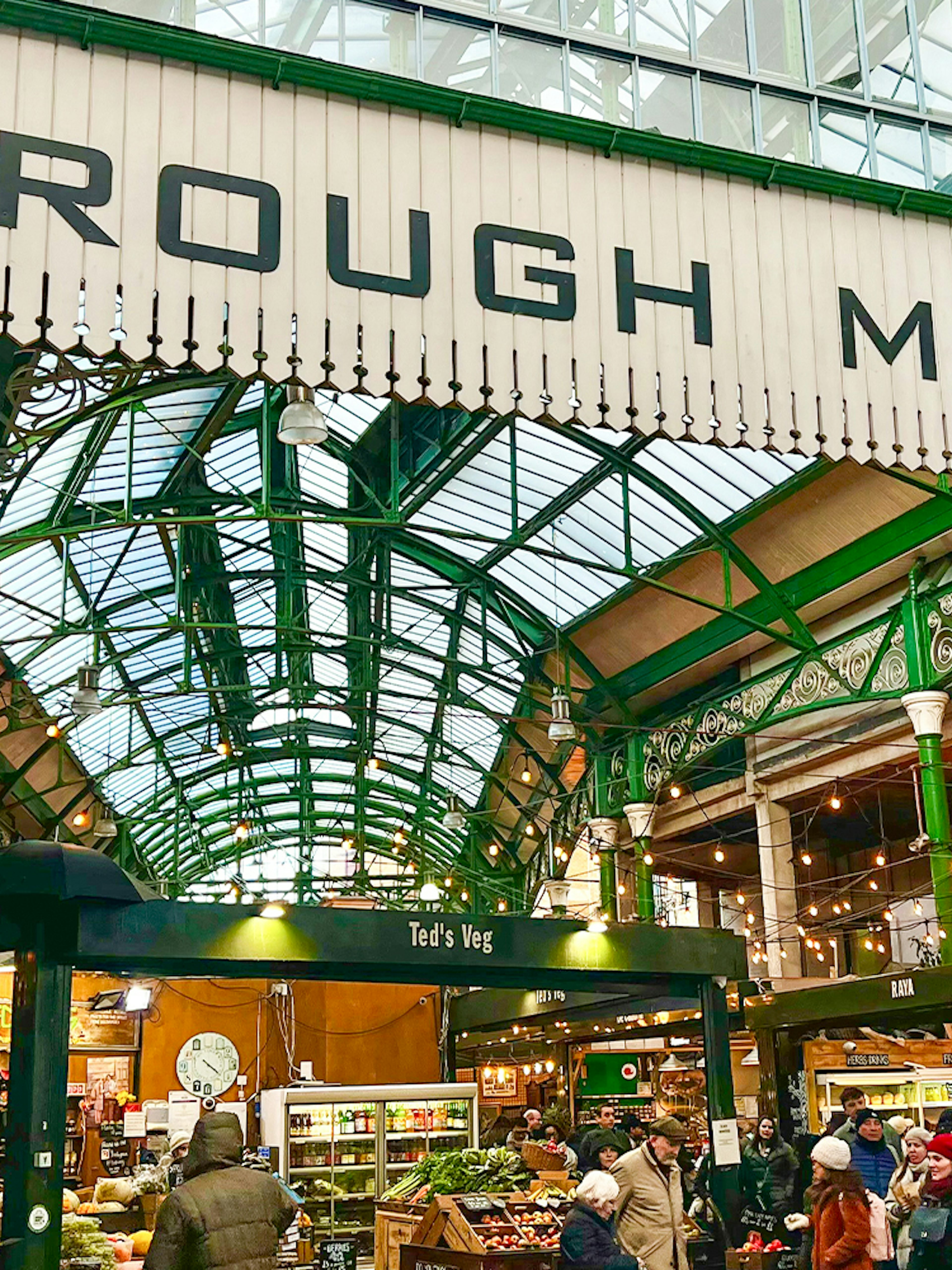 Borough Market entrance with visitors exploring food stalls in London.