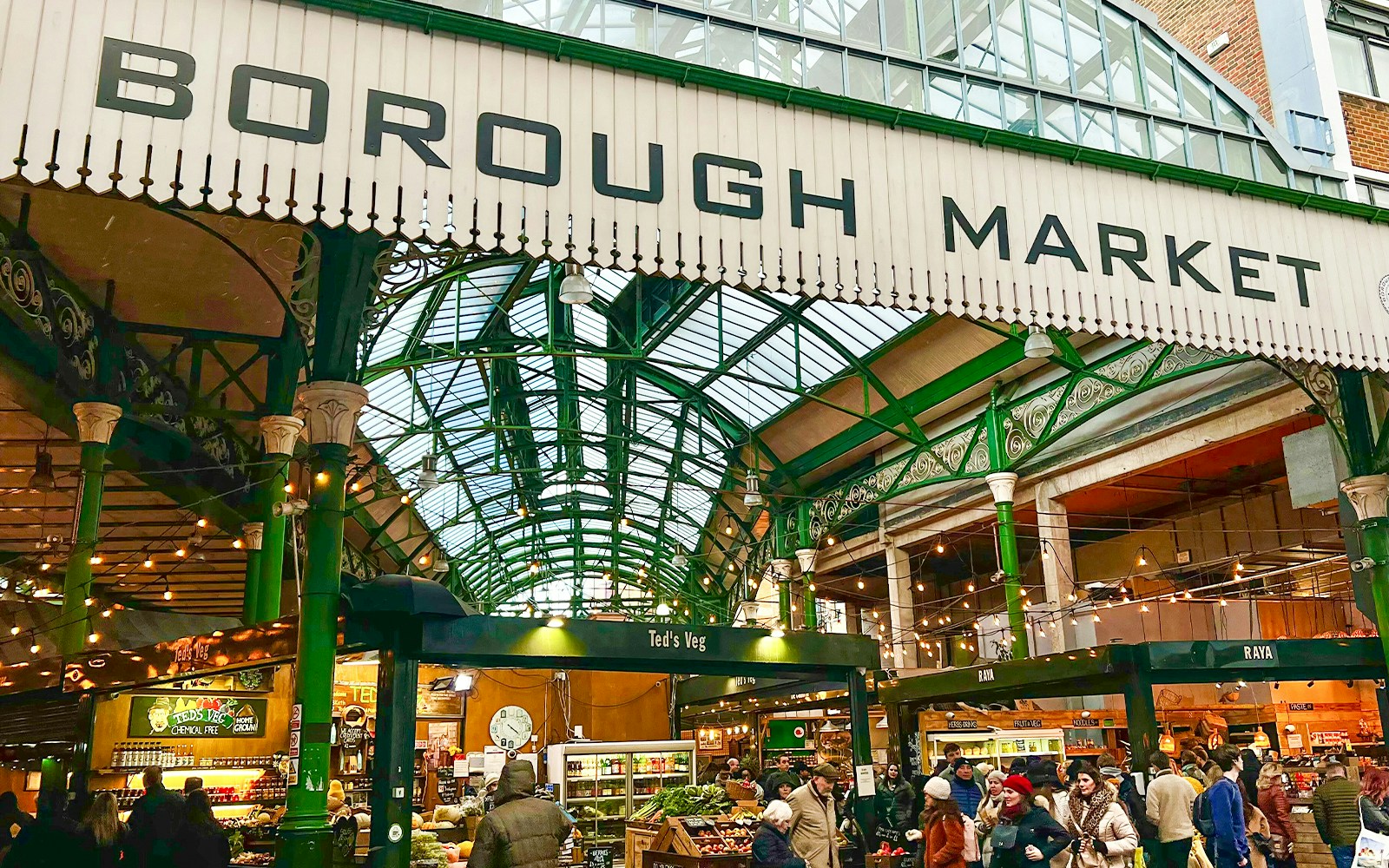 Borough Market entrance with visitors exploring food stalls in London.