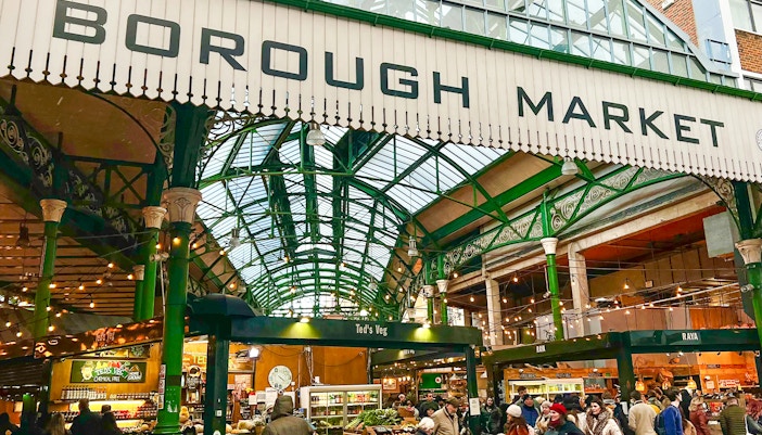 Borough Market entrance with visitors exploring food stalls in London.
