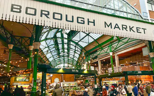 Borough Market entrance with visitors exploring food stalls in London.