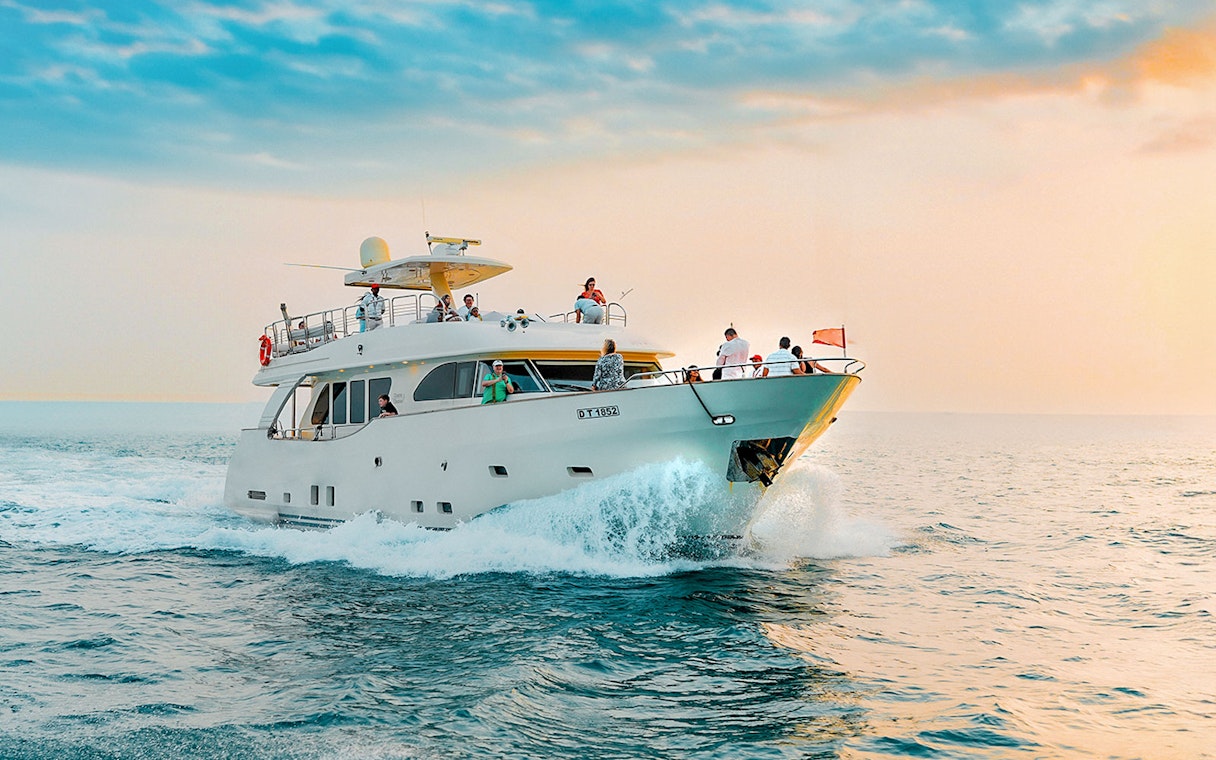 Yacht cruising on open water during sunset with passengers enjoying the view.