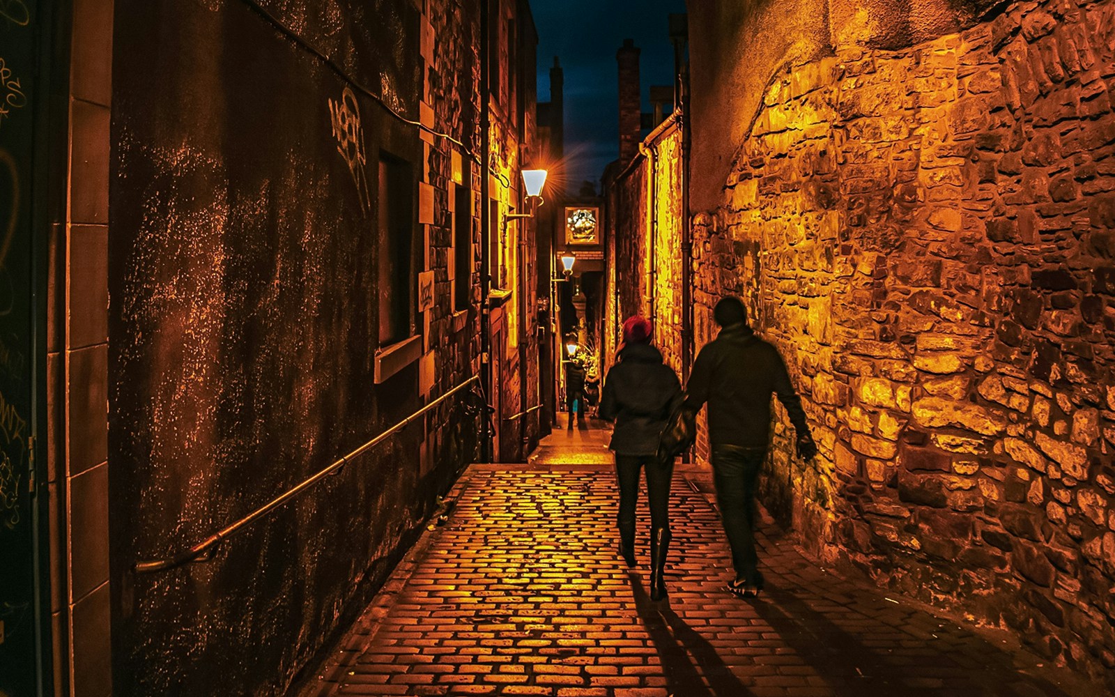 Couple walking through dimly lit cobblestone alley on Extreme Paranormal Activity Tour.