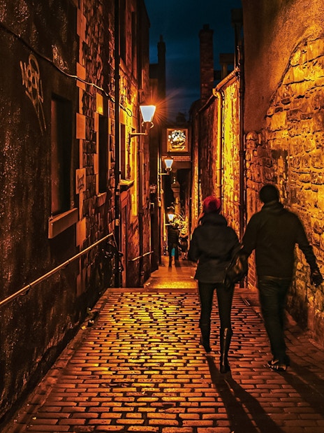 Couple walking through dimly lit cobblestone alley on Extreme Paranormal Activity Tour.