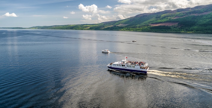 Cruise ship on Loch Ness, Scotland with scenic hills in the background.