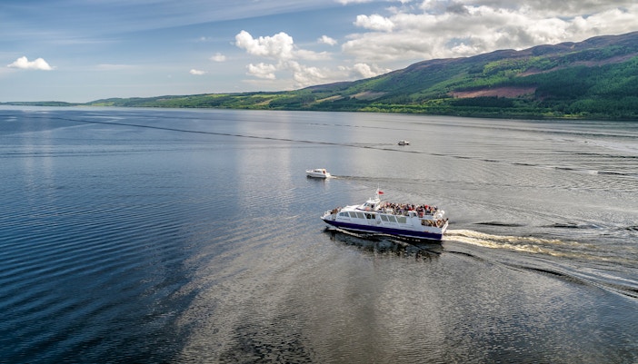 Cruise ship on Loch Ness, Scotland with scenic hills in the background.