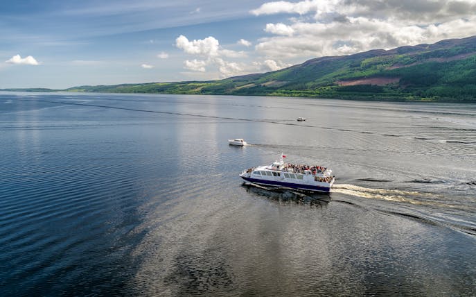 Cruise ship on Loch Ness, Scotland with scenic hills in the background.