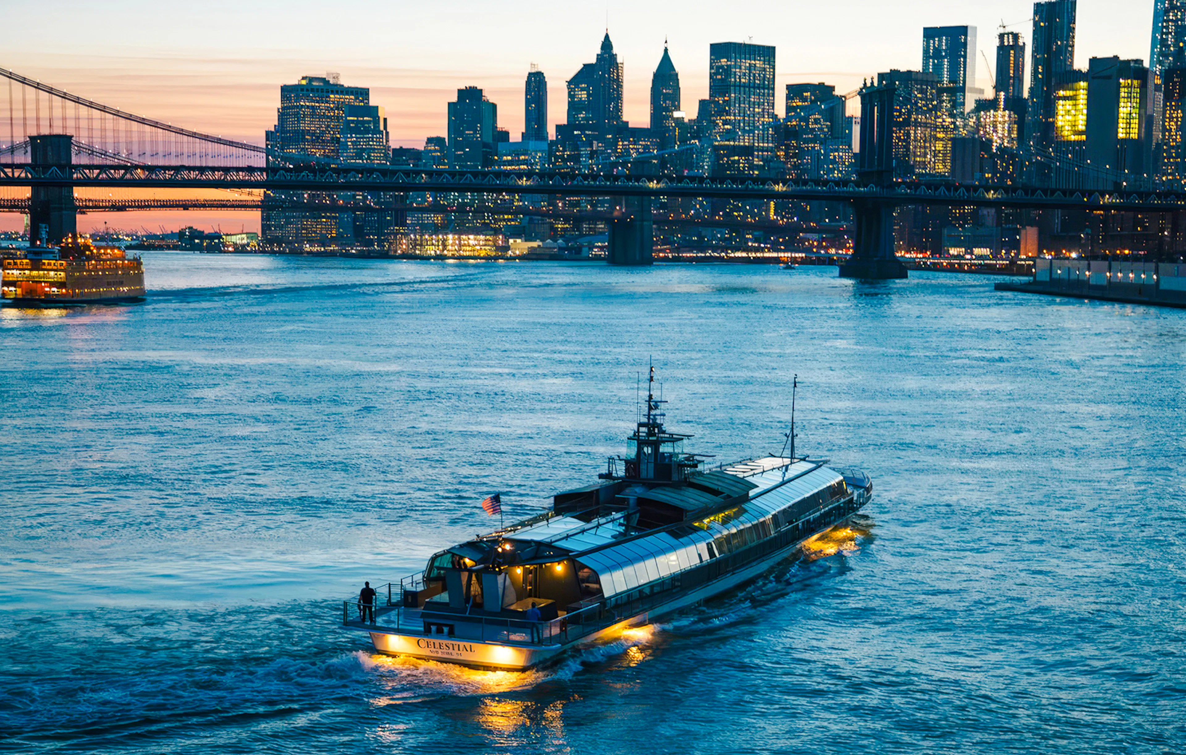 Dinner cruise boat on New York's East River with city skyline and bridge at sunset.