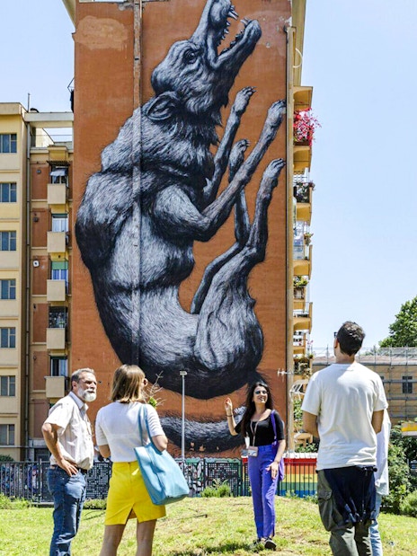 Tourists viewing street art mural on a building during Taste of Testaccio tour in Rome.