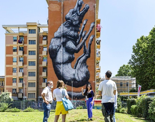 Tourists viewing street art mural on a building during Taste of Testaccio tour in Rome.