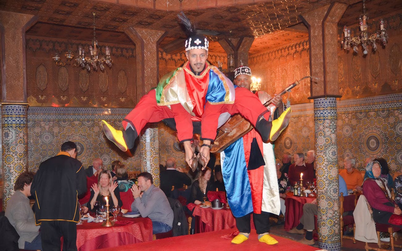 Performer in traditional attire jumping at Dar Essalam Moroccan Dinner show.
