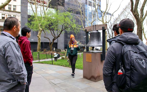Tour group at Ground Zero with guide near memorial bell.