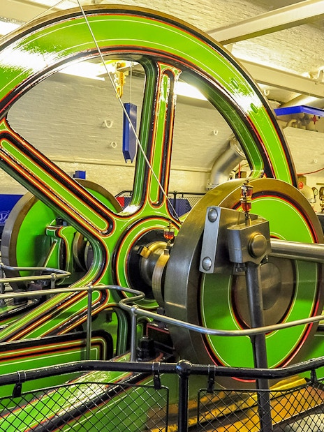 Tower Bridge Engine Room machinery with large green flywheel and pistons.