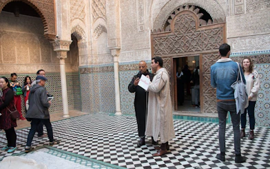 Visitors exploring the intricate architecture of Attarine Madrasa in Fes.