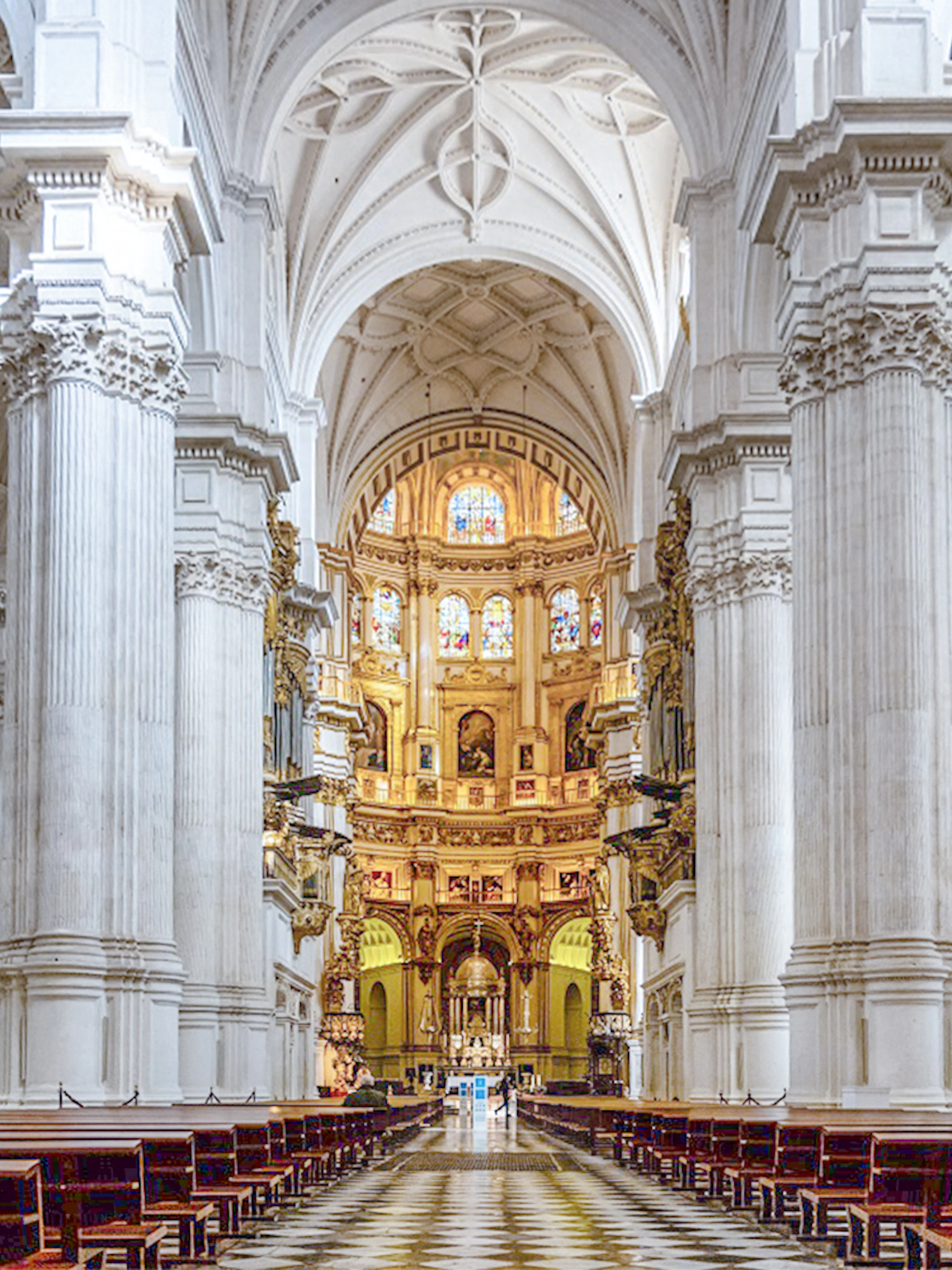 Granada Cathedral interior with ornate columns and stained glass windows.