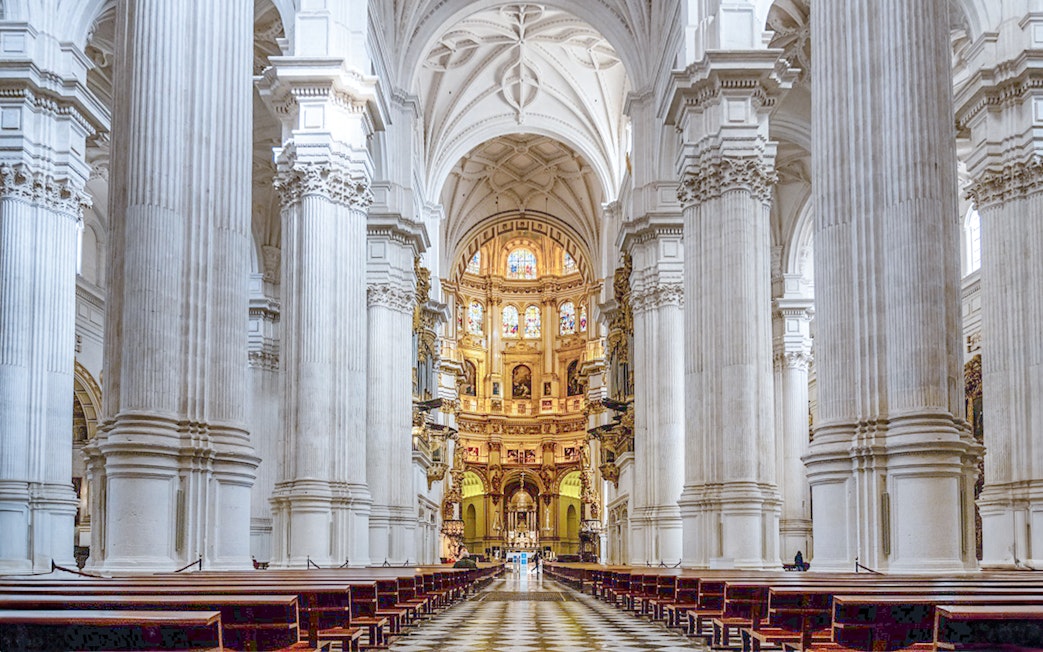 Granada Cathedral interior with ornate columns and stained glass windows.