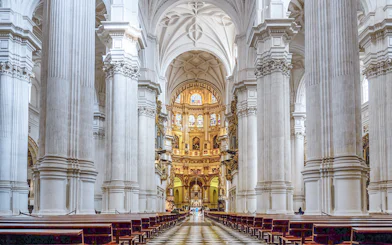 Granada Cathedral interior with ornate columns and stained glass windows.