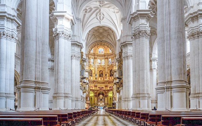 Granada Cathedral interior with ornate columns and stained glass windows.