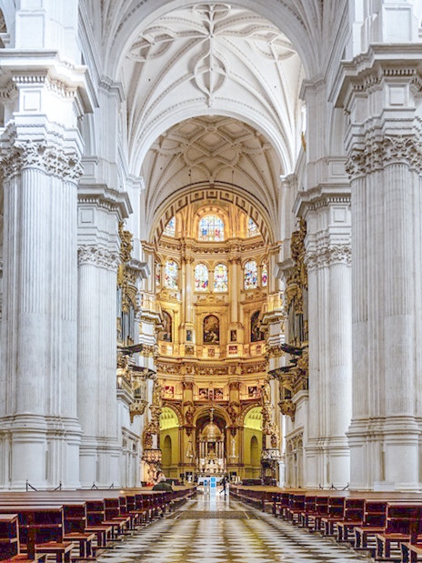 Granada Cathedral interior with ornate columns and stained glass windows.