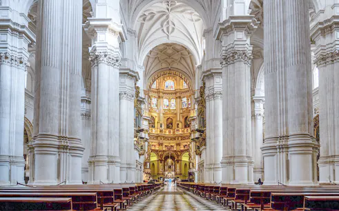 Granada Cathedral interior with ornate columns and stained glass windows.