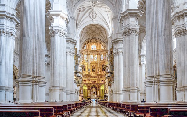 Granada Cathedral interior with ornate columns and stained glass windows.