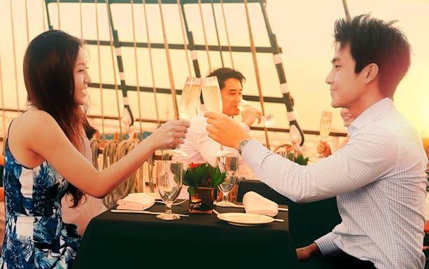 Couple toasting with champagne on The Royal Albatross sail at sunset.