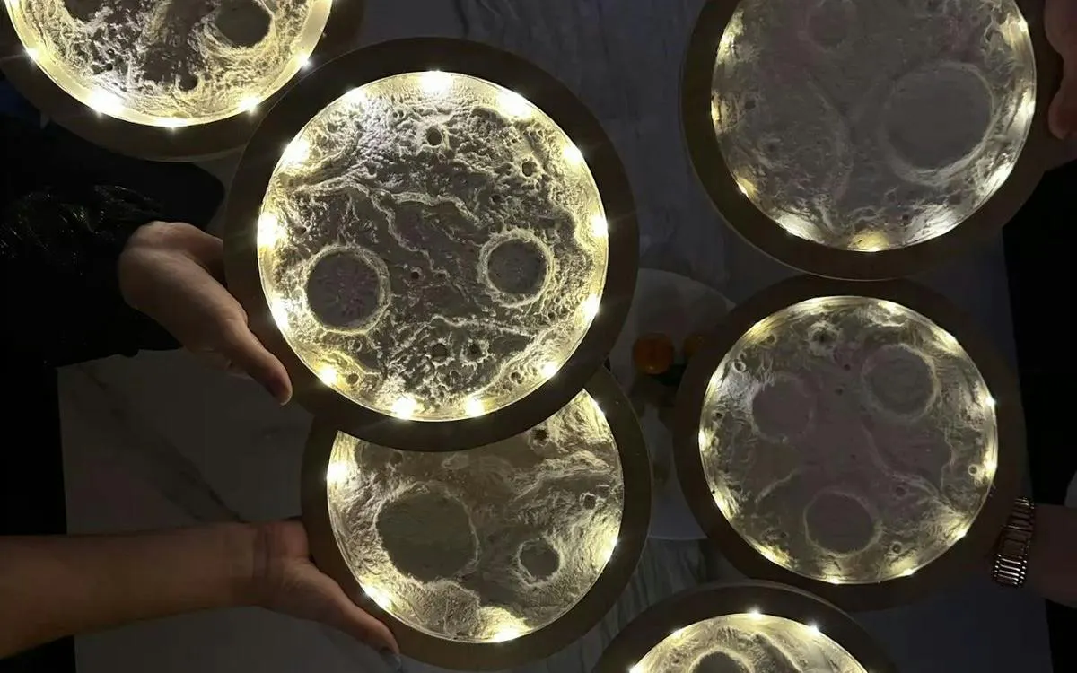 Illuminated moon-themed art pieces held by participants at Glow & Paint Night in Krakow.
