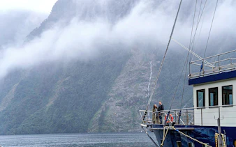 Cruise ship in Doubtful Sound with misty mountains in the background, Te Anau.
