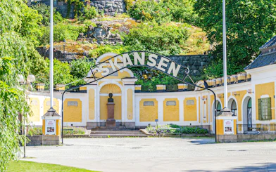 Exterior entrance of Skansen open-air museum in Stockholm, Sweden, with yellow buildings and greenery.