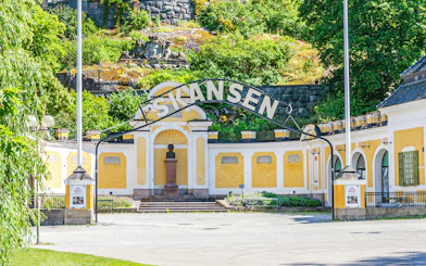 Exterior entrance of Skansen open-air museum in Stockholm, Sweden, with yellow buildings and greenery.