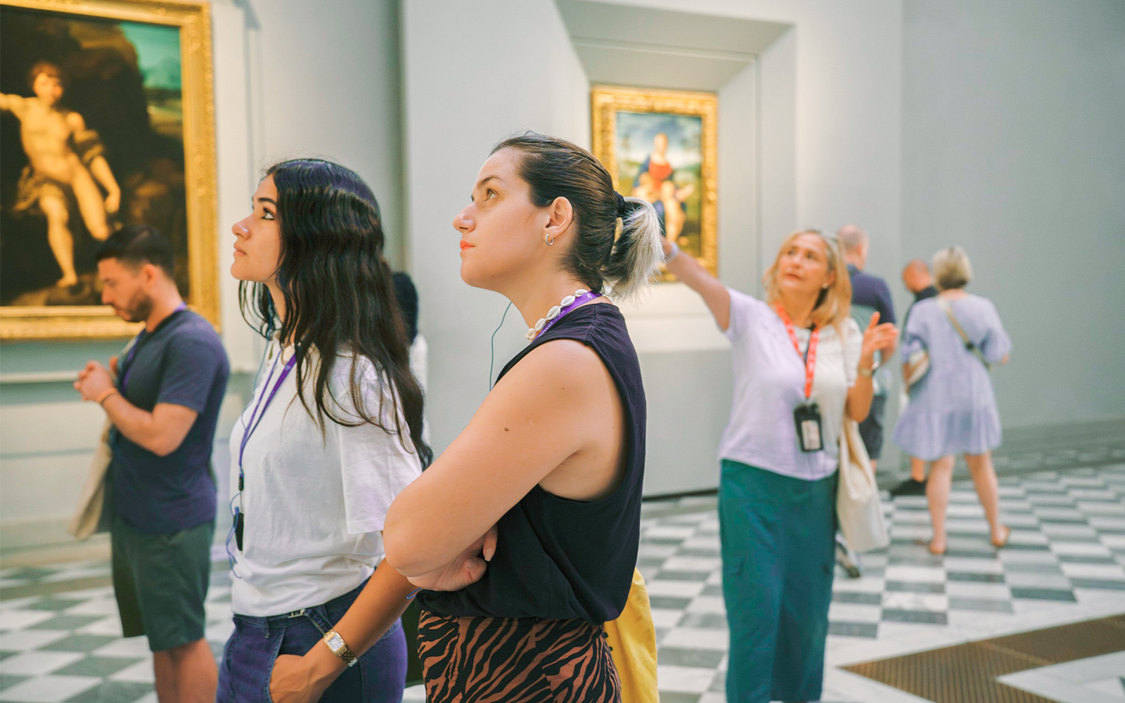 Woman admiring artwork in a gallery with others observing nearby.