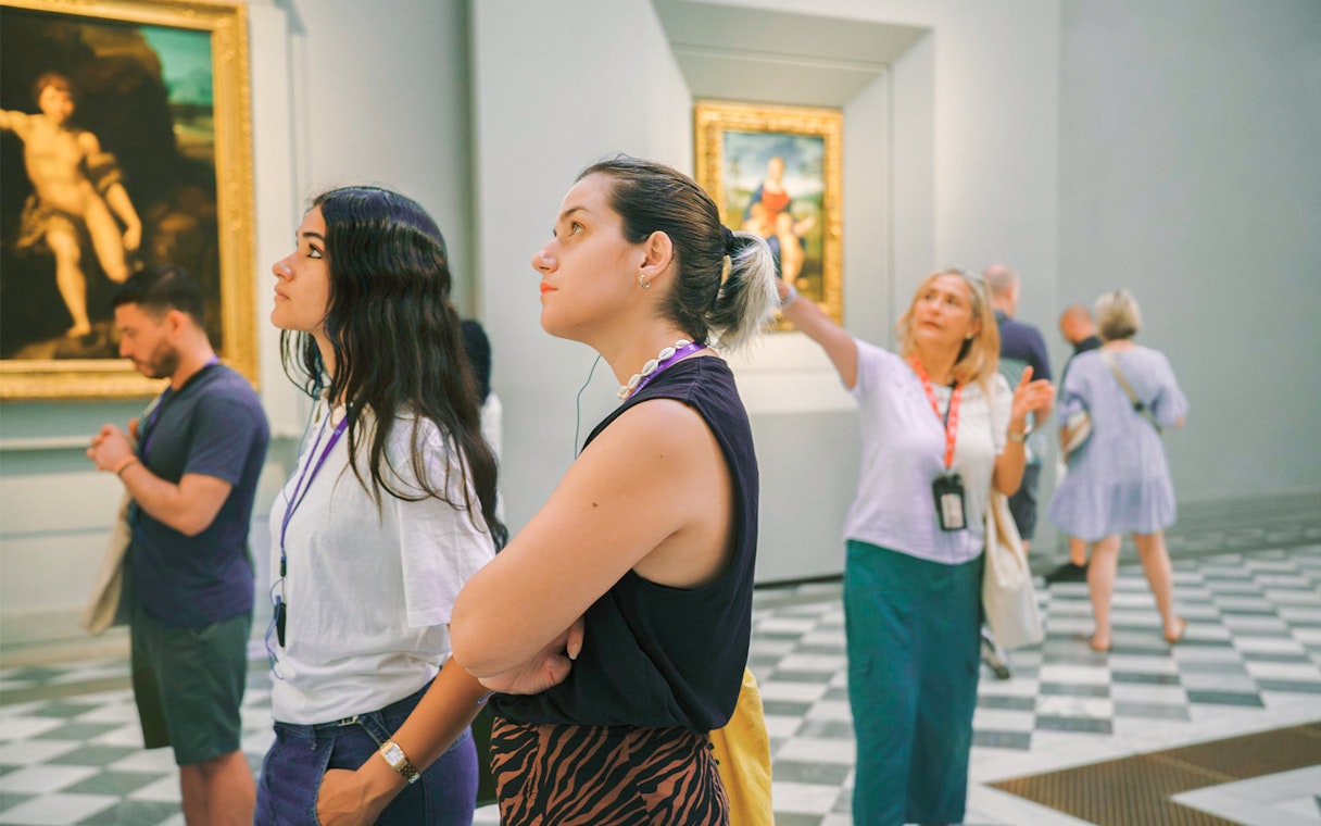 Woman admiring artwork in a gallery with others observing nearby.